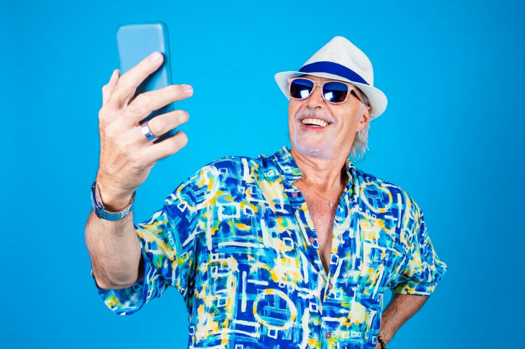 Senior man fashionable taking selfie on blue background